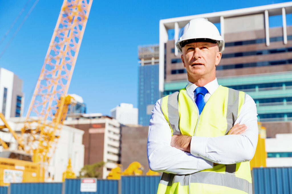 Man in suit wearing hard hat looking at building site