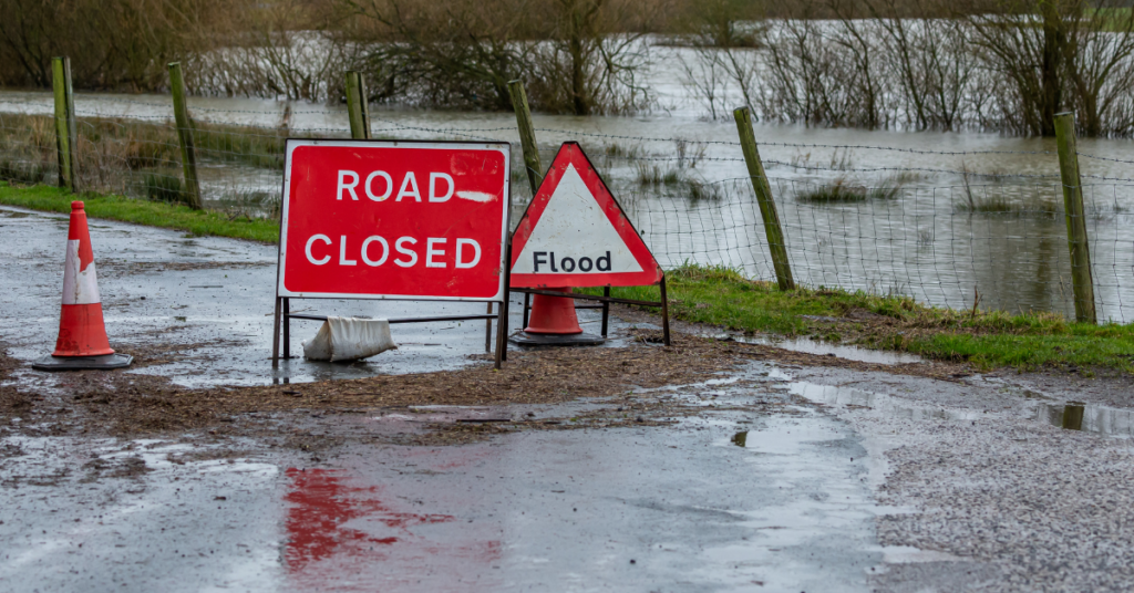 image of road flooded with warning signs and flood water rising